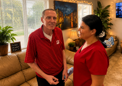 Male resident and female caregiver in red scrubs sharing a friendly conversation in the living room of a Florida ALF